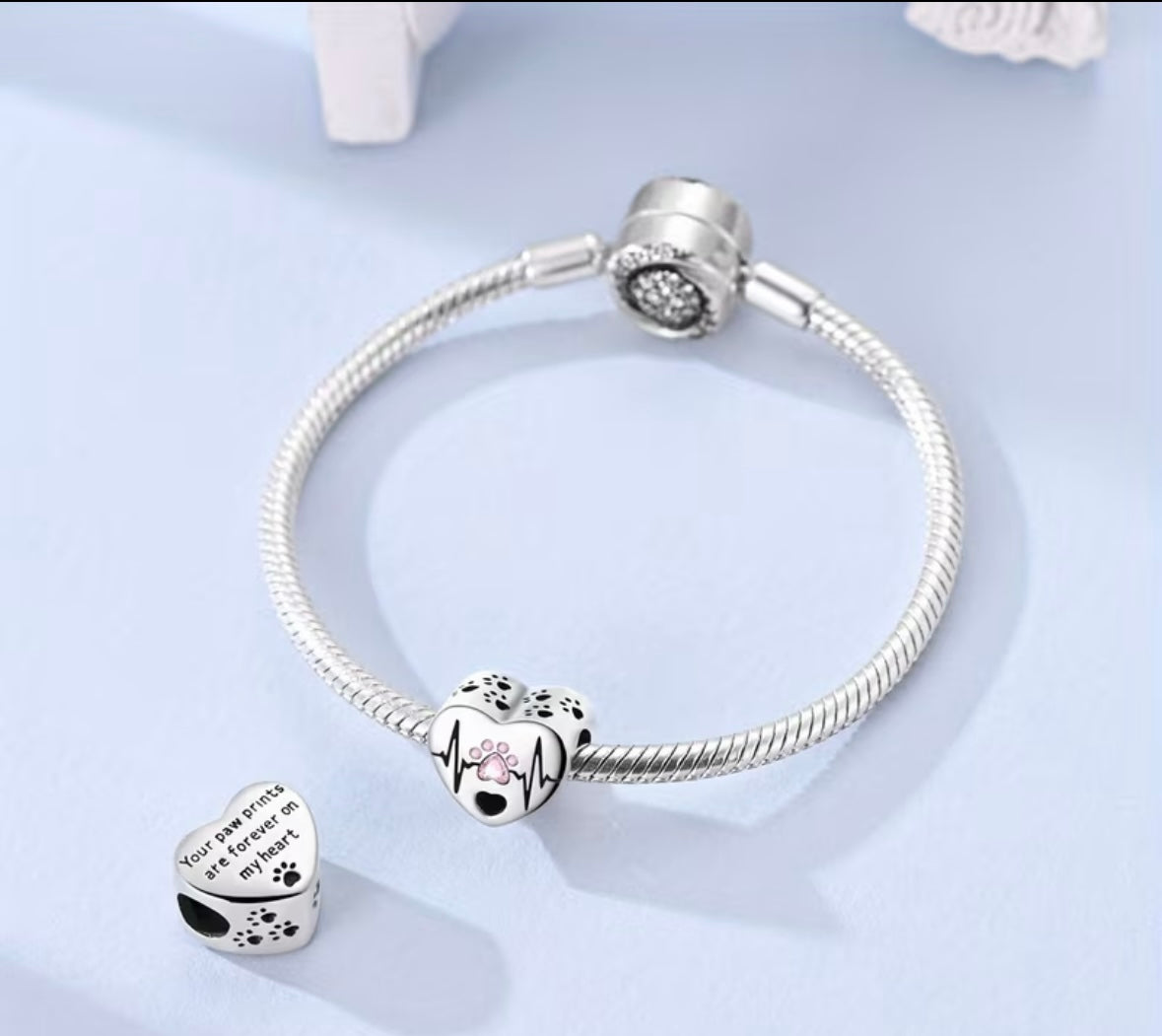 A silver plated minimalist heartbeat paw print charm